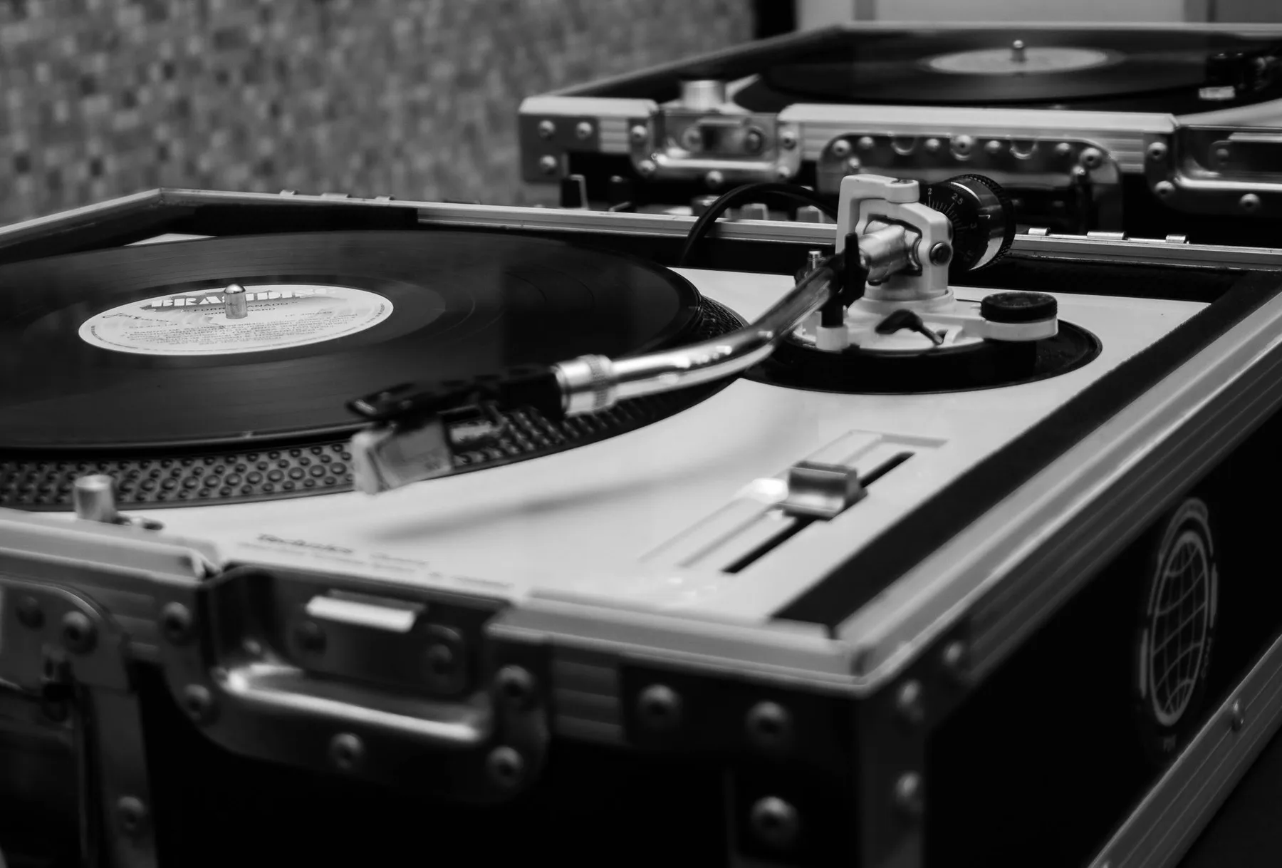 A vintage turntable setup in grayscale showcasing a vinyl record playing.