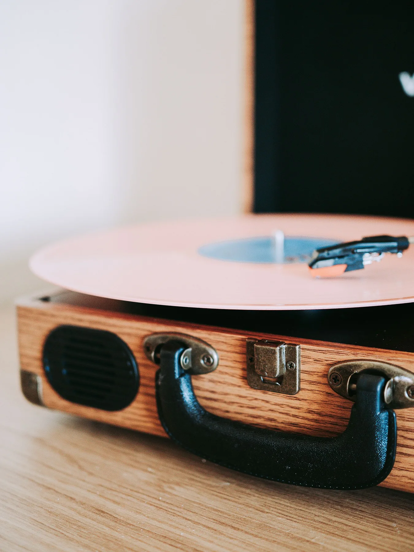 A stylish vintage wooden turntable playing a pink vinyl record in warm indoor light.