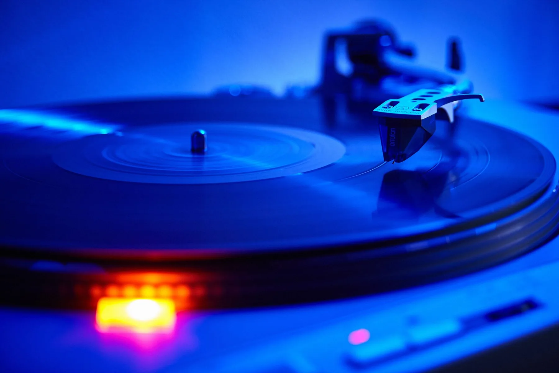 Vinyl record spinning on a turntable under cool blue light. ...